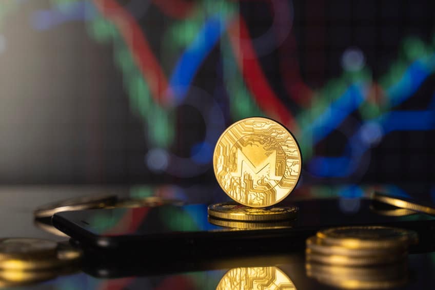 monero and virtual money concept. gold monero bitcoins on a stack of coins with chart of growing and falling valuance of a cryptocurrency. mining or blockchain technology.